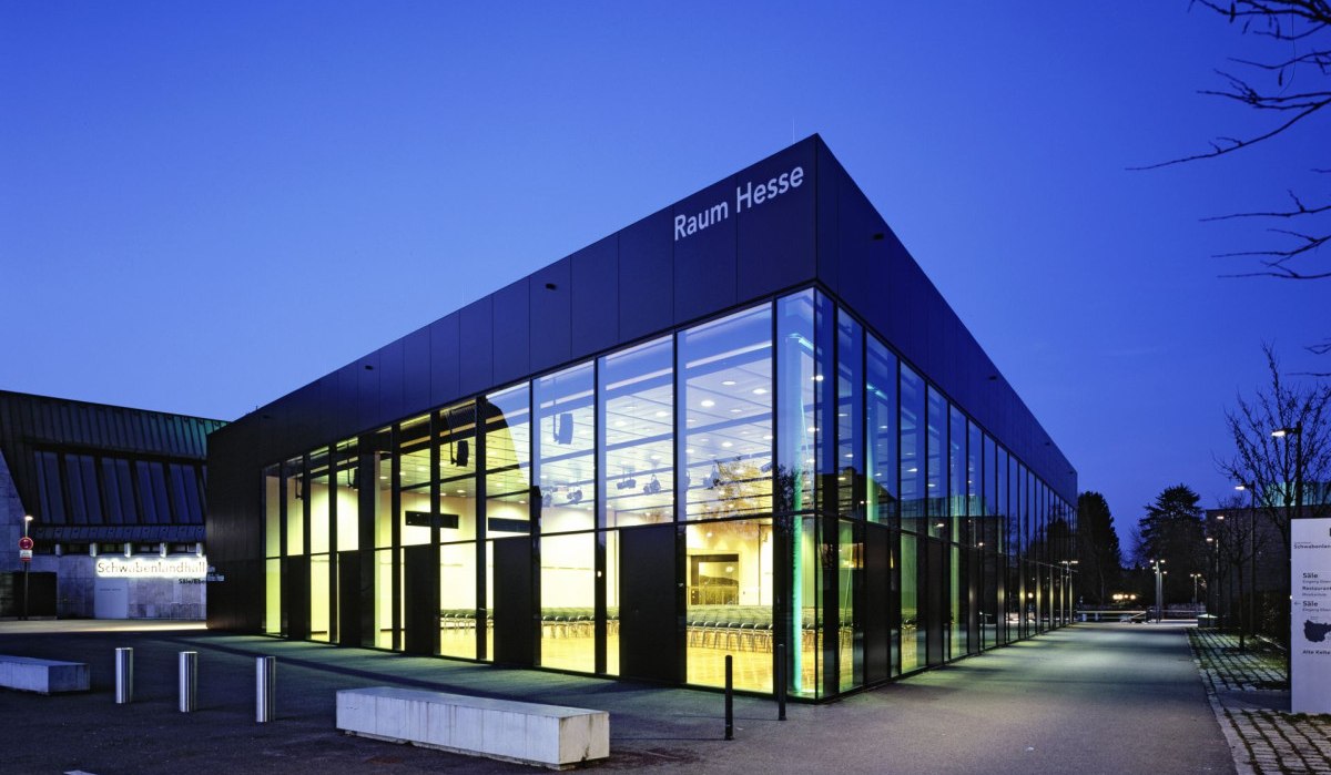 Die Schwabenlandhalle Fellbach bei Dämmerung. Moderne Glasfassade mit beleuchtetem Innenraum, umgeben von einem gepflasterten Weg und Bäumen., © Schwabenlandhalle Fellbach Die Schwabenlandhalle Fellbach bei Dämmerung. Moderne Glasfassade mit beleuchtetem Innenraum, umgeben von einem gepflasterten Weg und Bäumen., © Schwabenlandhalle Fellbach