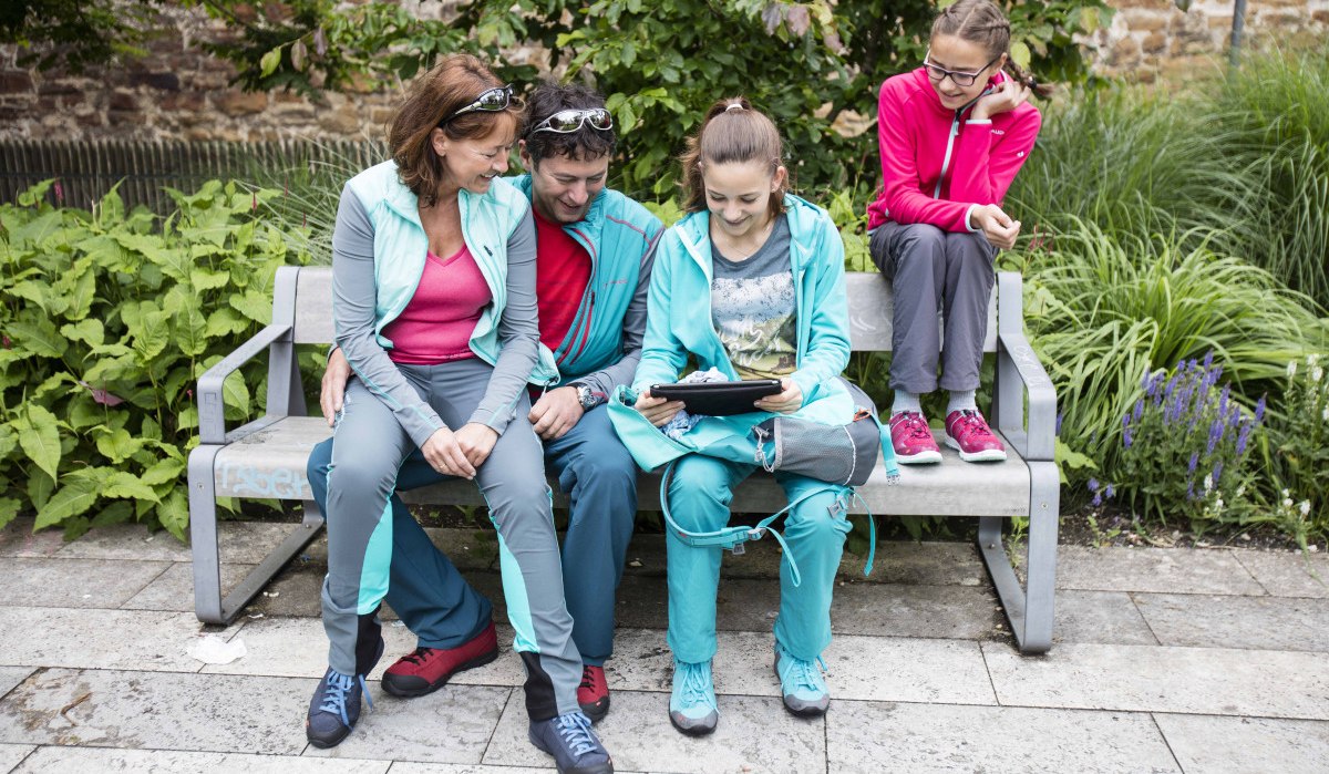 Vier Personen in sportlicher Kleidung sitzen auf einer Bank im Garten und betrachten gemeinsam ein Tablet., © Schwäbische Alb Tourismusverband e.V. Vier Personen in sportlicher Kleidung sitzen auf einer Bank im Garten und betrachten gemeinsam ein Tablet., © Schwäbische Alb Tourismusverband e.V.