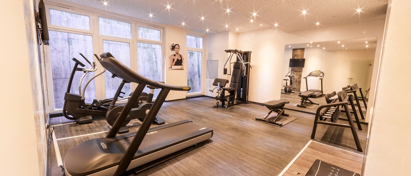 Ein moderner Fitnessraum mit Laufband, Crosstrainer, Kraftstation und Hanteln. Große Fenster und Spiegel sorgen für Helligkeit und Raumgefühl., © Plaza Residence Stuttgart-Ditzingen Ein moderner Fitnessraum mit Laufband, Crosstrainer, Kraftstation und Hanteln. Große Fenster und Spiegel sorgen für Helligkeit und Raumgefühl., © Plaza Residence Stuttgart-Ditzingen