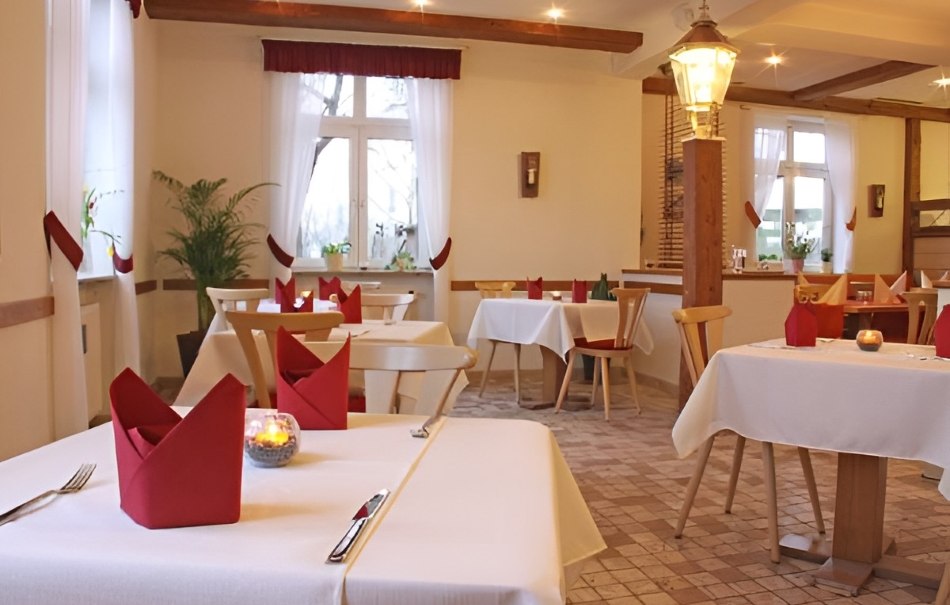 Gemütliches Restaurant mit weißen Tischdecken, roten Servietten und Kerzenlicht. Holzmöbel und Pflanzen schaffen eine einladende Atmosphäre., © Hotel Neuwirtshaus