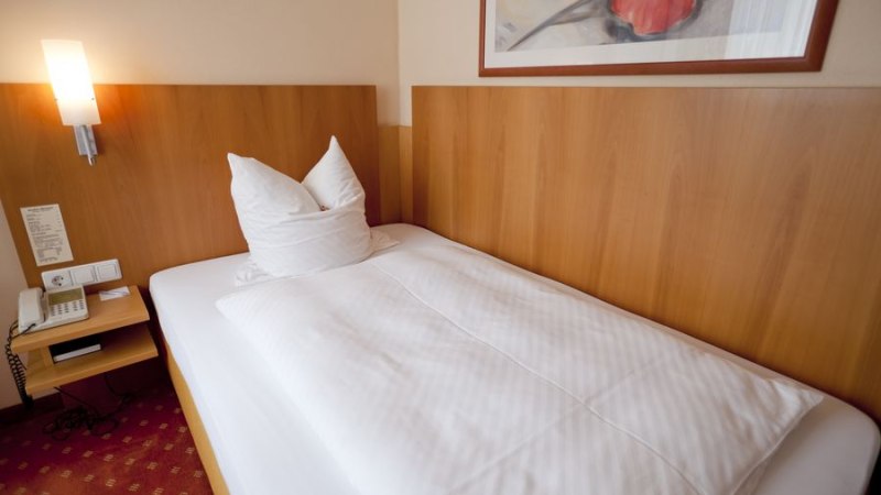 Ein gem&uuml;tliches Einzelzimmer mit einem Bett, einem Nachttisch mit Telefon und einem Bild an der Wand. Die Einrichtung ist schlicht und funktional., &copy; Hotel M&ouml;hringer Hof