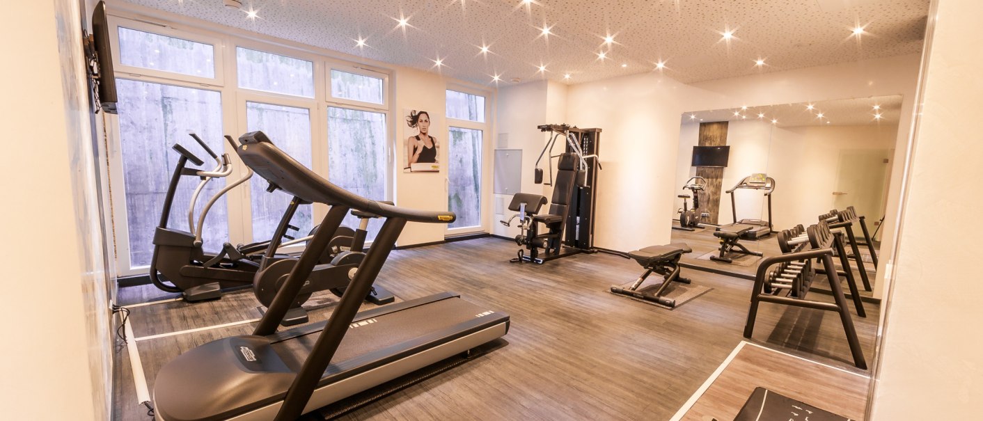 Heller Fitnessraum mit Laufband, Hanteln und Kraftgeräten. Große Fenster und Spiegel an den Wänden. Deckenbeleuchtung sorgt für eine angenehme Atmosphäre., © PLAZA Hotelgroup GmbH Heller Fitnessraum mit Laufband, Hanteln und Kraftgeräten. Große Fenster und Spiegel an den Wänden. Deckenbeleuchtung sorgt für eine angenehme Atmosphäre., © PLAZA Hotelgroup GmbH