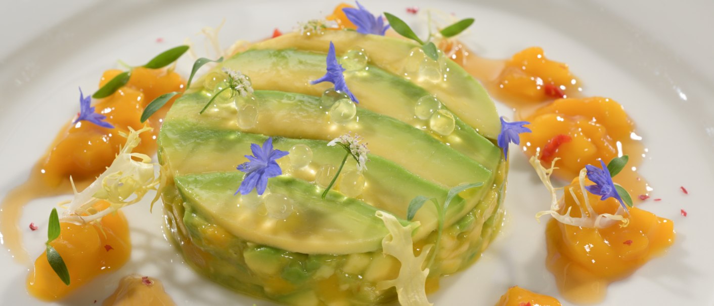 Avocado-Törtchen mit essbaren Blüten und Mangosauce, kunstvoll auf einem Teller angerichtet., © Landgasthof + Hotel Jagstmühle Avocado-Törtchen mit essbaren Blüten und Mangosauce, kunstvoll auf einem Teller angerichtet., © Landgasthof + Hotel Jagstmühle