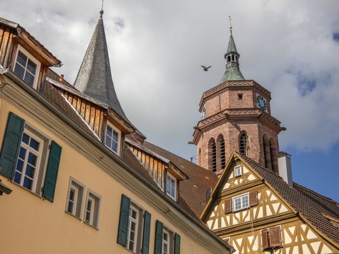 Historische Fachwerkh&auml;user und ein Kirchturm ragen in den blauen Himmel. Eine Taube fliegt vorbei, w&auml;hrend Wolken den Himmel schm&uuml;cken., &copy; Stadtverwaltung Weil der Stadt