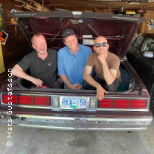 Drei Männer sitzen lachend im Kofferraum eines Autos in einer Garage. Sie wirken entspannt und fröhlich., © links im Bild Drei Männer sitzen lachend im Kofferraum eines Autos in einer Garage. Sie wirken entspannt und fröhlich., © links im Bild