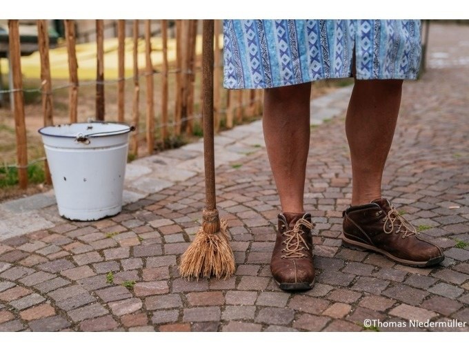 Beine einer Person in braunen Schuhen und blauem Rock stehen auf Kopfsteinpflaster mit Besen und Eimer., © Stuttgart Marketing GmbH, Thomas Niedermüller Beine einer Person in braunen Schuhen und blauem Rock stehen auf Kopfsteinpflaster mit Besen und Eimer., © Stuttgart Marketing GmbH, Thomas Niedermüller