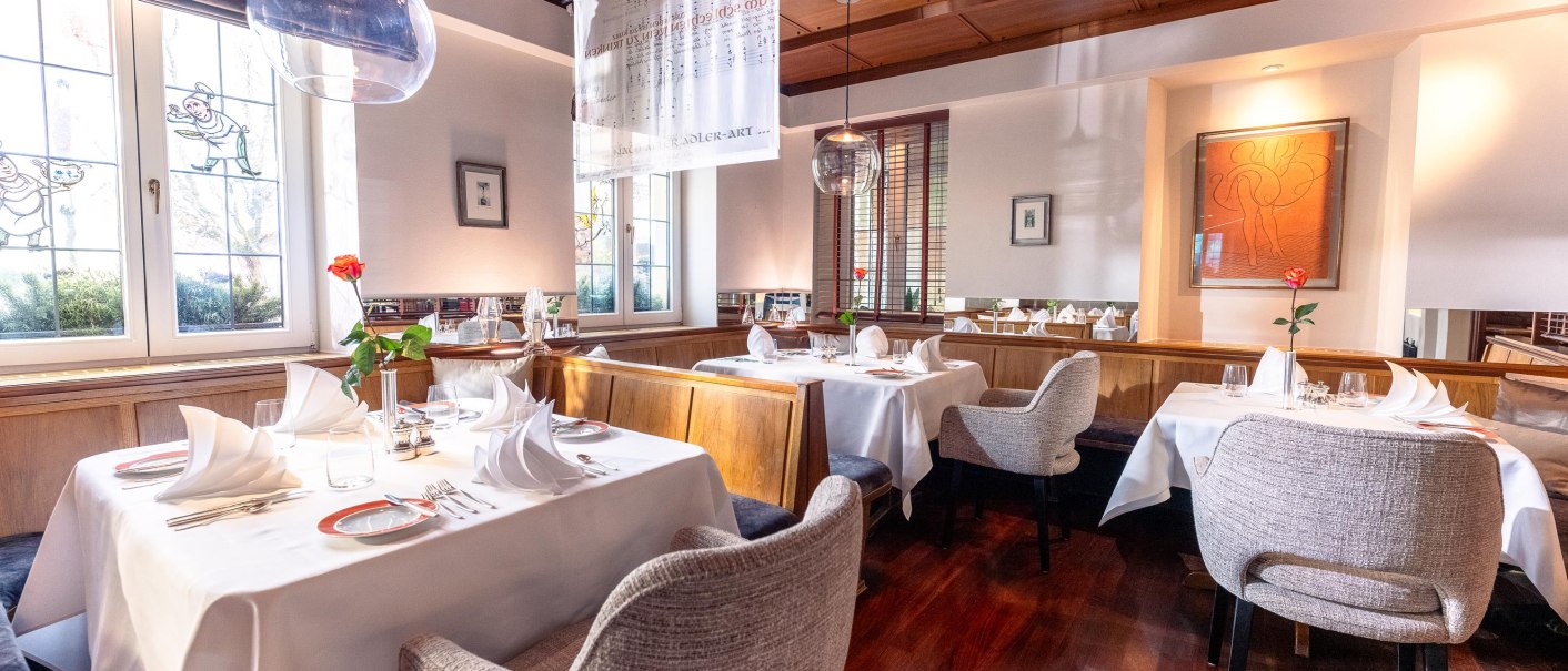 Elegantes Restaurant mit weißen Tischdecken, stilvollen Stühlen und moderner Kunst an den Wänden. Große Fenster lassen viel Licht herein., © Ringhotel Adler Asperg