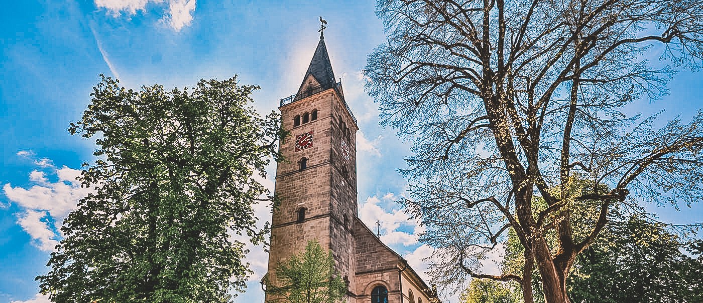 Eine Kirche mit hohem Turm, umgeben von Bäumen, bei sonnigem Wetter. Der Turm hat eine Uhr und ein spitzes Dach., © Stadt Welzheim Eine Kirche mit hohem Turm, umgeben von Bäumen, bei sonnigem Wetter. Der Turm hat eine Uhr und ein spitzes Dach., © Stadt Welzheim