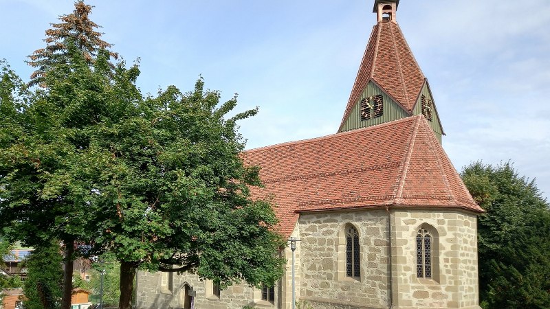 Kirche mit einem  roten Ziegeldach und kleinem Kirchturm, umgeben von gr&uuml;nen B&auml;umen und einem blauen Himmel im Hintergrund., &copy; Petra Natzkowski