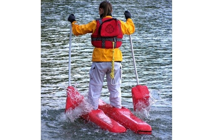 Person mit gelber Jacke und roter Schwimmweste steht auf roten Wasserschuhen im Wasser und hält zwei Stöcke., © Cool-Tours StattReisen