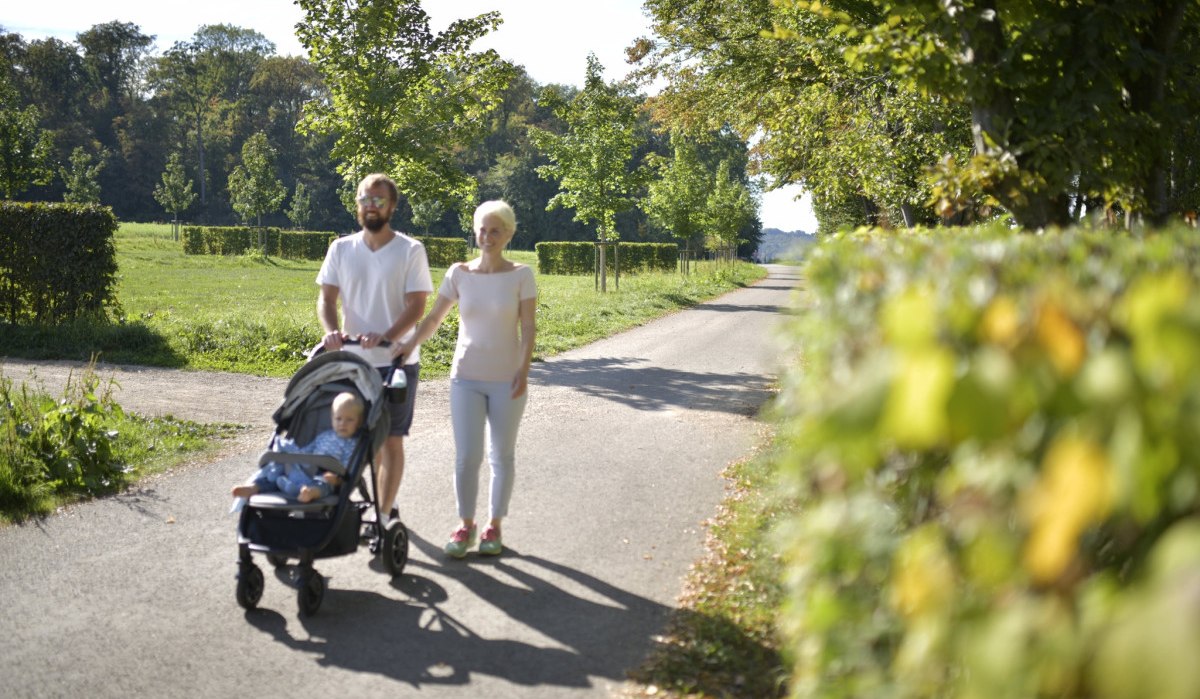 Ein Paar mit Kinderwagen spaziert auf einem sonnigen Weg, umgeben von Bäumen und Wiesen., © Landkreis Göppingen Ein Paar mit Kinderwagen spaziert auf einem sonnigen Weg, umgeben von Bäumen und Wiesen., © Landkreis Göppingen