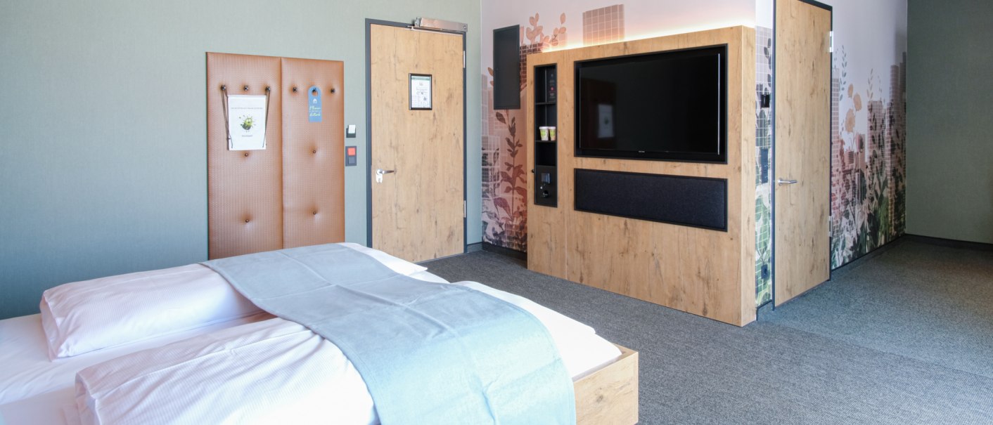 Modernes Hotelzimmer mit Doppelbett, Holzmöbeln, großem Fernseher und dekorativer Wandgestaltung., © 13 6 Design GmbH (Judenhof 10, 89073 Ulm) Modernes Hotelzimmer mit Doppelbett, Holzmöbeln, großem Fernseher und dekorativer Wandgestaltung., © 13 6 Design GmbH (Judenhof 10, 89073 Ulm)