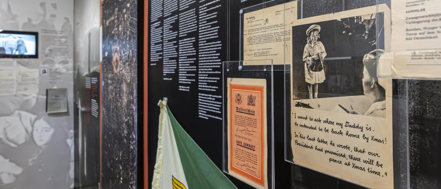 Ausstellungsraum im Polizeimuseum Stuttgart mit historischen Dokumenten, Fotos und Texttafeln an der Wand. Ein Bildschirm zeigt ein Video., © Stuttgart-Marketing GmbH, Sarah Schmid