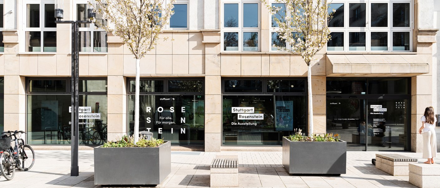 Eingang zur Ausstellung Stuttgart Rosenstein mit Glasfront, Schriftzug und Bäumen. Eine Person steht rechts, Fahrräder links., © Stadt Stuttgart / Dominique Brewing