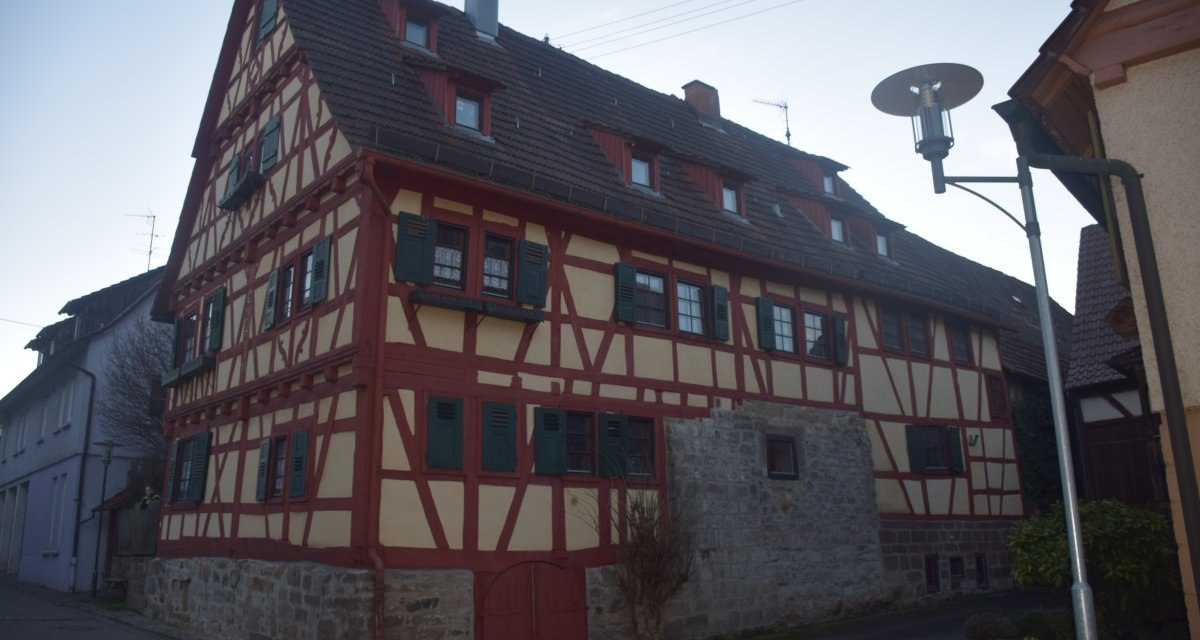 Fachwerkhaus mit roten Balken und grünen Fensterläden in einer schmalen Straße. Eine Straßenlaterne steht rechts im Bild., © Land der 1000 Hügel - Kraichgau-Stromberg Fachwerkhaus mit roten Balken und grünen Fensterläden in einer schmalen Straße. Eine Straßenlaterne steht rechts im Bild., © Land der 1000 Hügel - Kraichgau-Stromberg