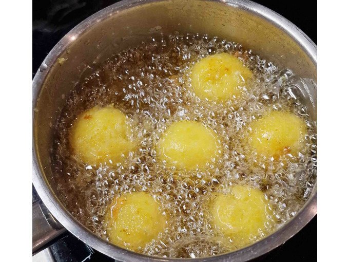Sechs goldbraune Teigbällchen werden in einem Topf mit sprudelndem Öl frittiert. Die Oberfläche ist knusprig und gleichmäßig gebräunt., © Kultweine-Kochwelten-Kunstücke - Kochschule Sonja Lenz Sechs goldbraune Teigbällchen werden in einem Topf mit sprudelndem Öl frittiert. Die Oberfläche ist knusprig und gleichmäßig gebräunt., © Kultweine-Kochwelten-Kunstücke - Kochschule Sonja Lenz