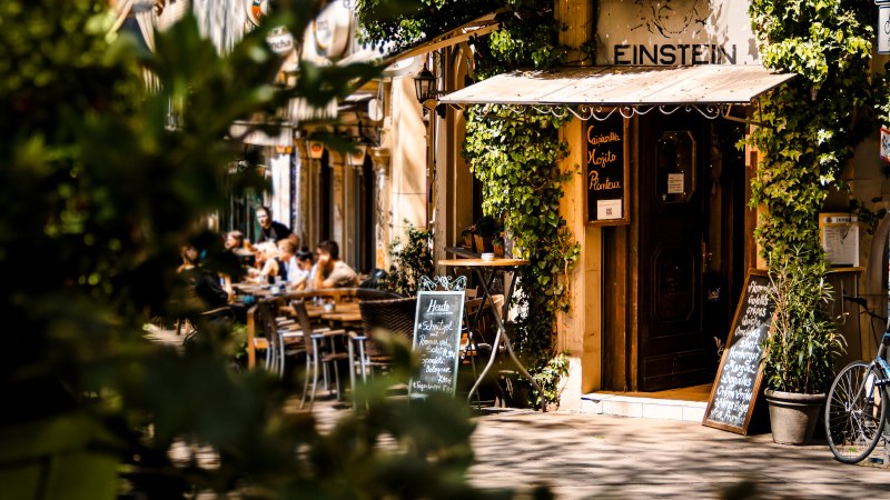 Ein gemütliches Café namens Einstein mit Pflanzen und Fahrrädern. Menschen sitzen draußen und genießen das Wetter., © SMG Stuttgart Marketing GmbH - Sarah Schmid Ein gemütliches Café namens Einstein mit Pflanzen und Fahrrädern. Menschen sitzen draußen und genießen das Wetter., © SMG Stuttgart Marketing GmbH - Sarah Schmid