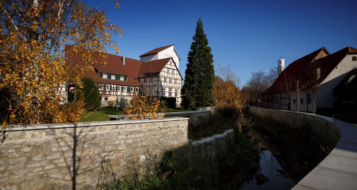 Fachwerkh&auml;user mit roten D&auml;chern und ein kleiner Bach, umgeben von herbstlichen B&auml;umen, unter einem klaren blauen Himmel., &copy; Stoppel