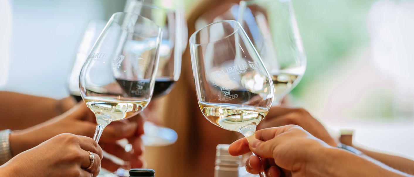 Mehrere Personen stoßen mit gefüllten Weingläsern an, im Hintergrund unscharf eine Person. Es herrscht eine fröhliche Atmosphäre., © Stuttgart-Marketing GmbH, Thomas Niedermüller