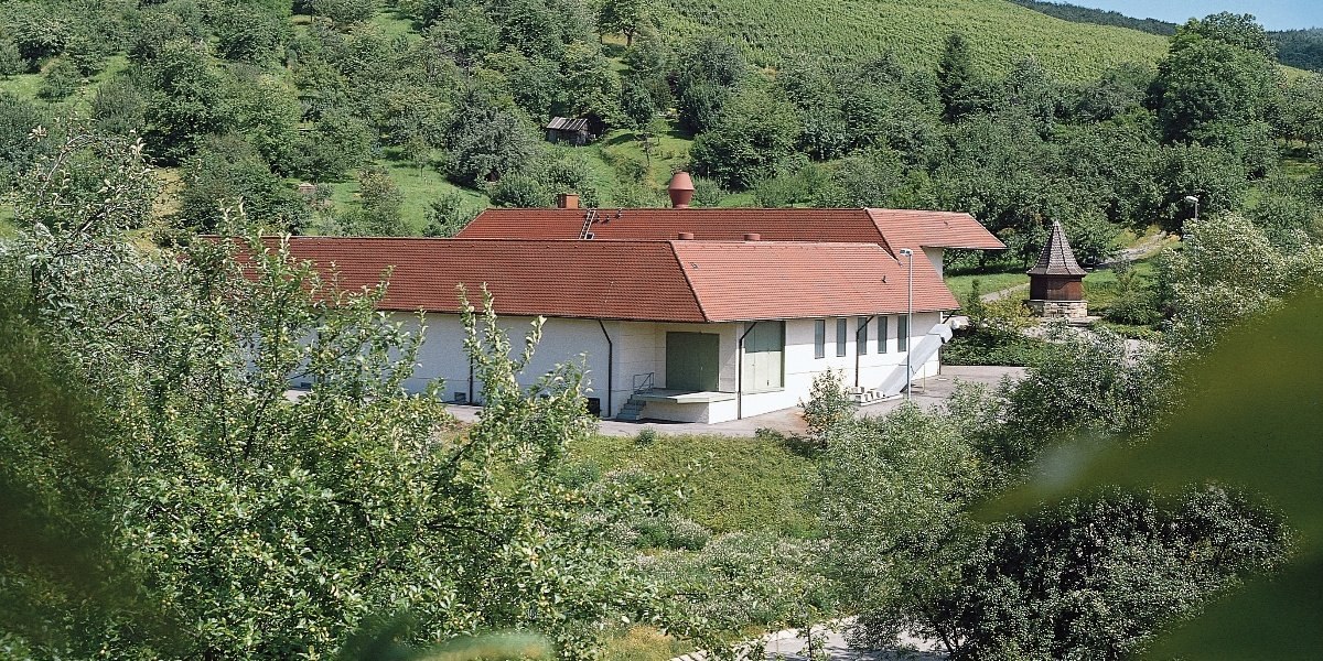 Ein Geb&auml;ude mit rotem Dach steht in einer gr&uuml;nen, bewaldeten Landschaft. Im Hintergrund sind H&uuml;gel und B&auml;ume zu sehen., &copy; Stuttgart-Marketing GmbH