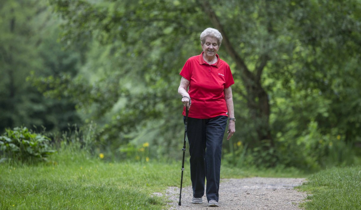 Ältere Frau in rotem Shirt spaziert mit Gehstock auf einem Waldweg, umgeben von grüner Natur., © Schwäbische Alb Tourismusverband e.V. Ältere Frau in rotem Shirt spaziert mit Gehstock auf einem Waldweg, umgeben von grüner Natur., © Schwäbische Alb Tourismusverband e.V.