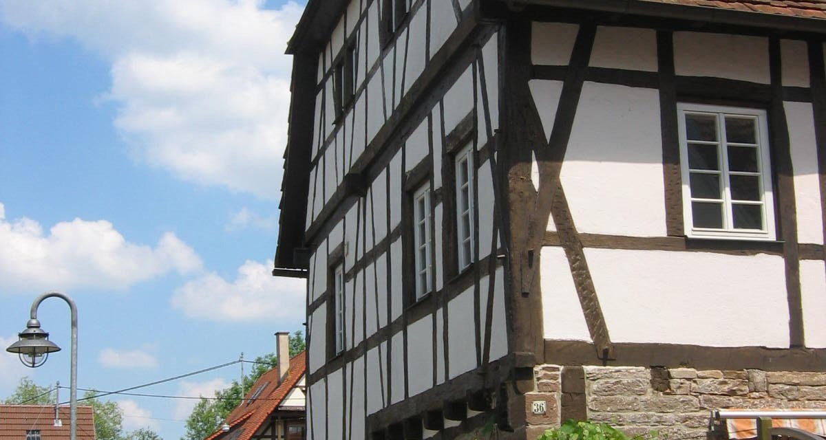 Fachwerkhaus mit rotem Ziegeldach, umgeben von weiteren Häusern und blühender Vegetation. Der Himmel ist blau mit einigen Wolken., © Land der 1000 Hügel - Kraichgau-Stromberg Fachwerkhaus mit rotem Ziegeldach, umgeben von weiteren Häusern und blühender Vegetation. Der Himmel ist blau mit einigen Wolken., © Land der 1000 Hügel - Kraichgau-Stromberg