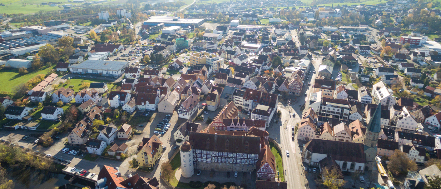 Luftaufnahme von Gaildorf mit Fachwerkhäusern, Kirche und umliegenden Gebäuden. Die Stadt ist von grünen Feldern umgeben., © Stadt Gaildorf