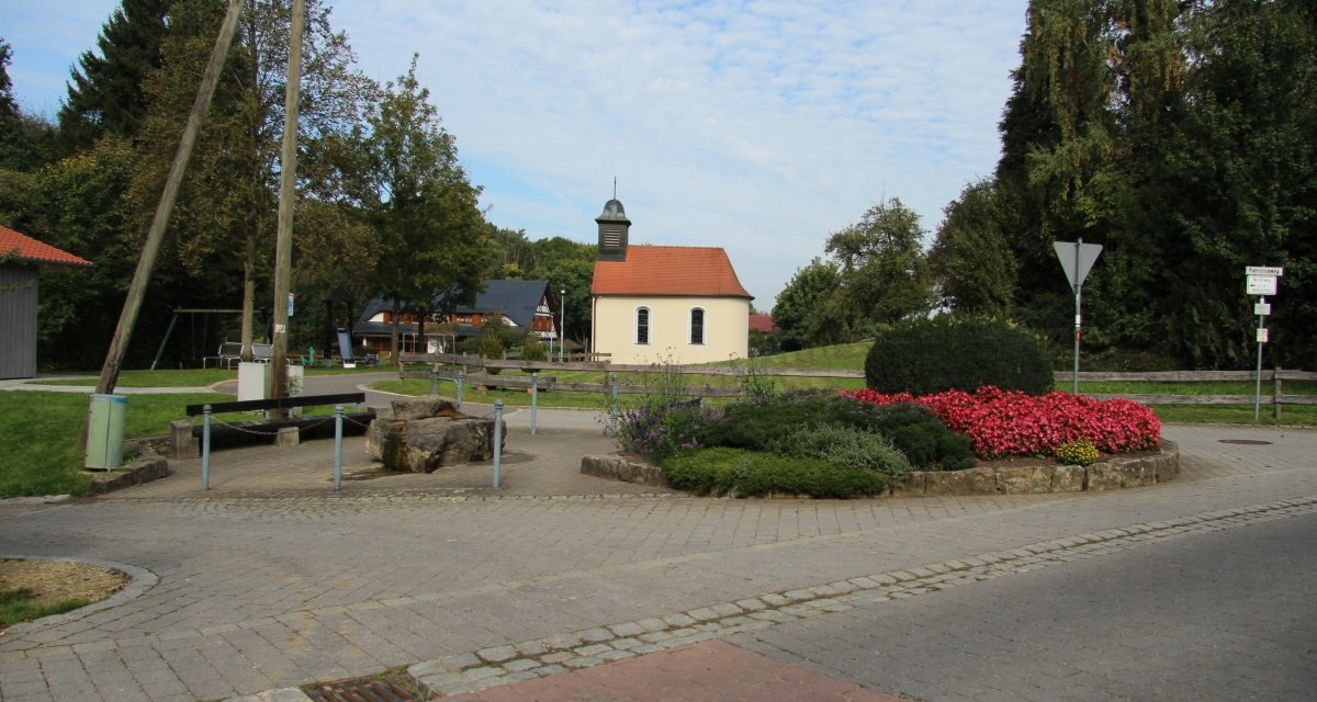 Kleiner Platz auf dem ein bepflanztes Beet steht. Im Hintergrund steht eine kleine Kapelle., © Foto: Frieder Kopper Kleiner Platz auf dem ein bepflanztes Beet steht. Im Hintergrund steht eine kleine Kapelle., © Foto: Frieder Kopper