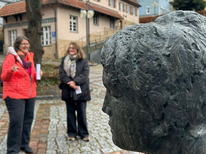 Zwei Frauen stehen neben einer Bronzeb&uuml;ste im Freien. Im Hintergrund ist ein Geb&auml;ude mit Fachwerk zu sehen., &copy; PlochingenInfo