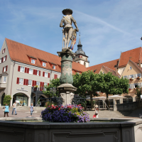 Marktbrunnen mit Statue auf einem belebten Platz, umgeben von historischen Geb&auml;uden mit roten D&auml;chern und B&auml;umen., &copy; Stuttgart-Marketing GmbH