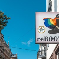Ein Schild mit einem Stiefel und einer Regenbogenflagge, daneben die Aufschrift 'reBOOTS'. Im Hintergrund sind Geb&auml;ude und ein Baum zu sehen., &copy; SMG, Sarah Schmid