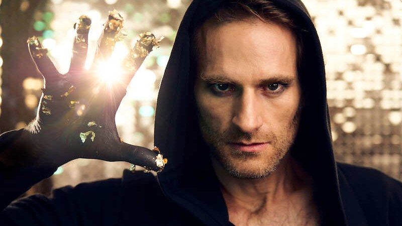 Ein Mann in einem schwarzen Kapuzenpullover h&auml;lt seine Hand mit goldenen Akzenten in die Kamera. Licht scheint durch seine Finger und erzeugt einen magischen Effekt., &copy; EMT Event-Media-Tec GmbH