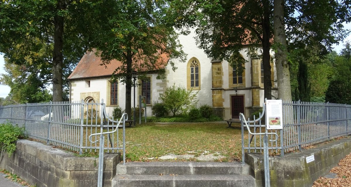 Die Michaelskirche in Oberböbingen, umgeben von Bäumen und einem Metallzaun. Herbstlaub bedeckt den Boden vor der Kirche., © Foto: Cornelia Steinbach Die Michaelskirche in Oberböbingen, umgeben von Bäumen und einem Metallzaun. Herbstlaub bedeckt den Boden vor der Kirche., © Foto: Cornelia Steinbach
