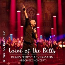 Ein S&auml;nger steht auf einer B&uuml;hne mit erhobenem Arm, im Hintergrund ein Chor. Der Text "Carol of the Bells" und "Abschiedskonzert" ist sichtbar., &copy; links im Bild
