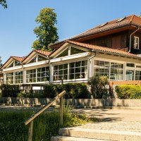 Ein modernes Gebäude mit großen Fenstern und rotem Dach, umgeben von Bäumen und Grünflächen. Der Himmel ist klar und blau., © Stuttgart-Marketing GmbH, Sarah Schmid Ein modernes Gebäude mit großen Fenstern und rotem Dach, umgeben von Bäumen und Grünflächen. Der Himmel ist klar und blau., © Stuttgart-Marketing GmbH, Sarah Schmid