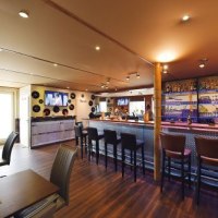 Moderne Bar mit langer Theke, Barhockern und Schallplatten-Dekor. Gemütliche Sitzbereiche und ein Fernseher an der Wand., © Bar Freddchen Moderne Bar mit langer Theke, Barhockern und Schallplatten-Dekor. Gemütliche Sitzbereiche und ein Fernseher an der Wand., © Bar Freddchen