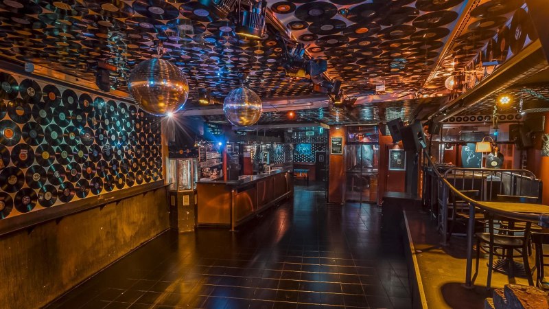 Club mit Schallplatten an W&auml;nden und Decke, Discokugeln und Bar. Stimmungsvolle Beleuchtung und leere Tanzfl&auml;che., &copy; Goldmarks, Stuttgart
