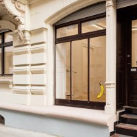 Eingang einer Galerie mit dem Schild 'Die Raumgalerie'. Eine Banane ist an der Glast&uuml;r angebracht. Das Geb&auml;ude hat eine verzierte Fassade., &copy; Dirk Wilhelmy Fotografie