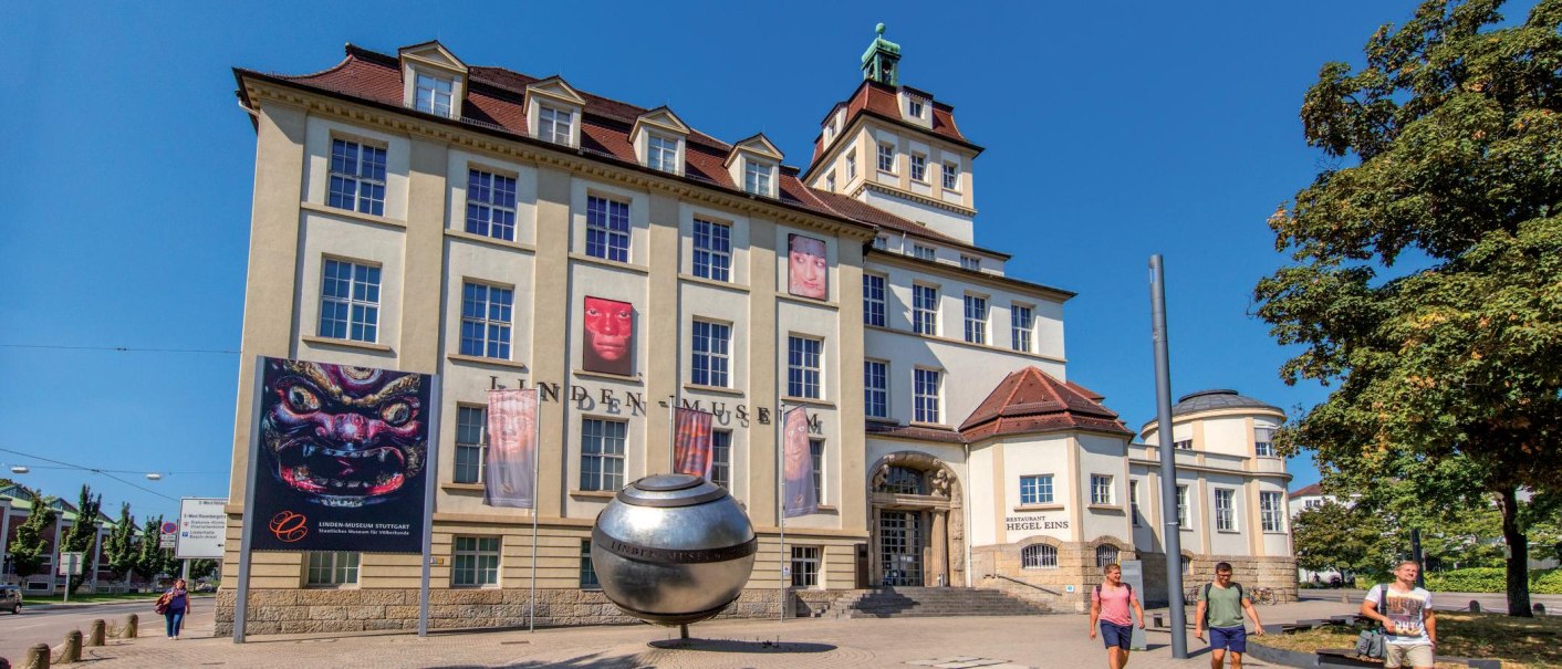 Das Linden-Museum in Stuttgart bei sonnigem Wetter. Vor dem Gebäude sind Plakate und eine große silberne Kugel zu sehen. Menschen spazieren vorbei., © Stuttgart-Marketing GmbH, Achim Mende Das Linden-Museum in Stuttgart bei sonnigem Wetter. Vor dem Gebäude sind Plakate und eine große silberne Kugel zu sehen. Menschen spazieren vorbei., © Stuttgart-Marketing GmbH, Achim Mende