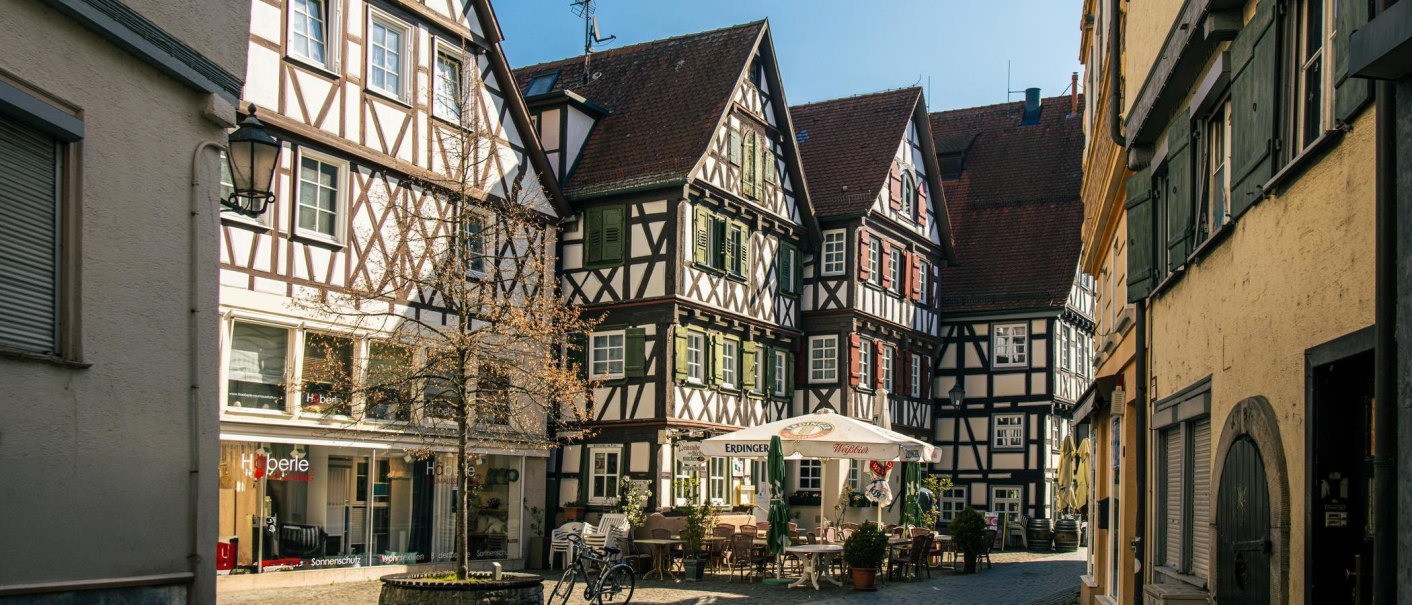 Fachwerkhäuser am Schorndorfer Marktplatz. Ein Café mit Sonnenschirmen und Tischen im Freien lädt zum Verweilen ein., © Stuttgart-Marketing GmbH, Sarah Schmid