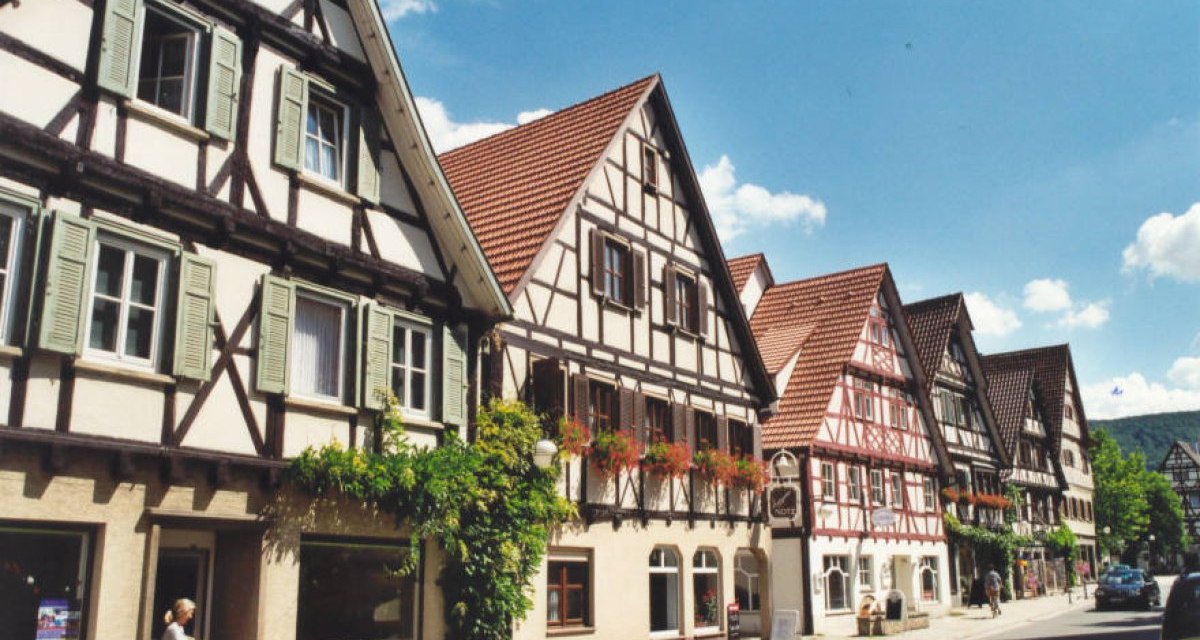 Reihe von Fachwerkhäusern in Dettingen an der Erms, Deutschland, bei sonnigem Wetter. Eine Person steht vor einem der Häuser., © Gemeinde Dettingen an der Erms Reihe von Fachwerkhäusern in Dettingen an der Erms, Deutschland, bei sonnigem Wetter. Eine Person steht vor einem der Häuser., © Gemeinde Dettingen an der Erms