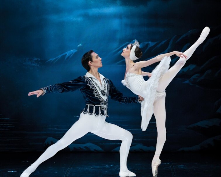 Zwei Balletttänzer in eleganten Kostümen führen eine Szene aus Schwanensee auf. Der Hintergrund zeigt eine nächtliche Landschaft., © Stadthalle Leonberg