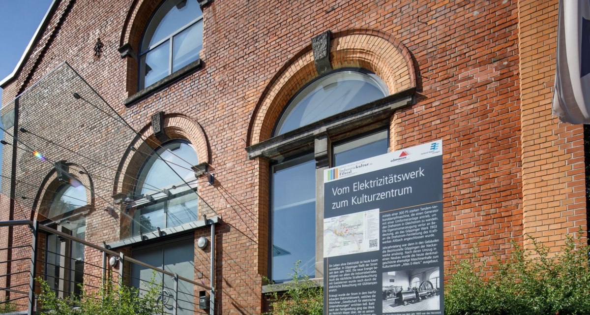 Backstein-Gebäude mit großen Fenstern, Schild informiert über die Umwandlung eines Elektrizitätswerks in ein Kulturzentrum. Teil der Route der Industriekultur., © Stoppel Backstein-Gebäude mit großen Fenstern, Schild informiert über die Umwandlung eines Elektrizitätswerks in ein Kulturzentrum. Teil der Route der Industriekultur., © Stoppel