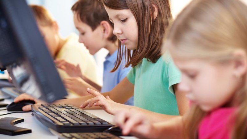 Kinder sitzen nebeneinander an Computern und tippen konzentriert auf Tastaturen. Sie sind in einem Klassenzimmer oder Computerraum., &copy; Fotalia