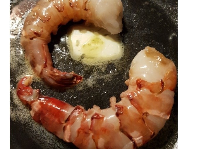 Zwei rohe Garnelen in einer Pfanne mit schmelzender Butter, bereit zum Kochen., © Kultweine-Kochwelten-Kunstücke - Kochschule Sonja Lenz Zwei rohe Garnelen in einer Pfanne mit schmelzender Butter, bereit zum Kochen., © Kultweine-Kochwelten-Kunstücke - Kochschule Sonja Lenz