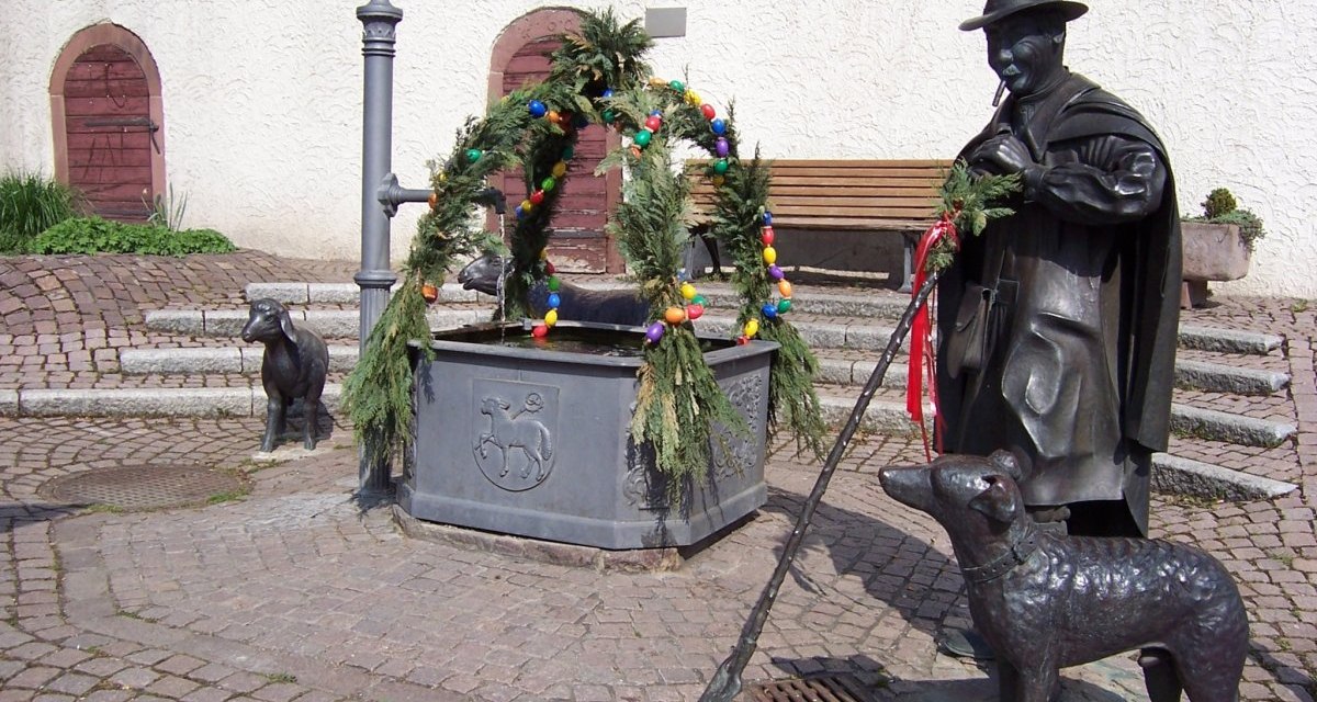 Der Osterbrunnen in Schafhausen ist mit bunten Eiern und grünen Zweigen geschmückt. Bronzefiguren eines Hirten, eines Hundes und eines Schafes umgeben den Brunnen., © Natur.Nah. Schönbuch & Heckengäu Der Osterbrunnen in Schafhausen ist mit bunten Eiern und grünen Zweigen geschmückt. Bronzefiguren eines Hirten, eines Hundes und eines Schafes umgeben den Brunnen., © Natur.Nah. Schönbuch & Heckengäu