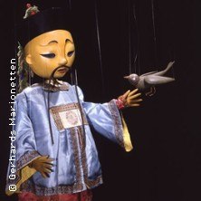 Eine Marionette in traditioneller Kleidung hält eine Nachtigall. Der Hintergrund ist dunkel, die Szene wirkt theatralisch., © links im Bild