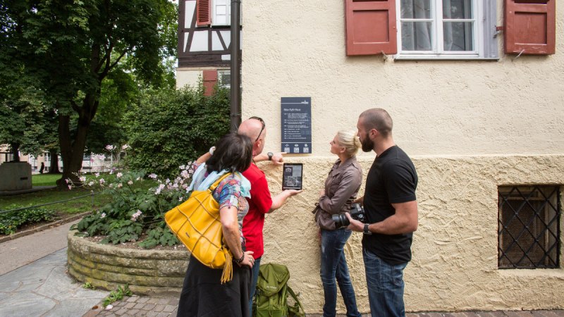 Vier Personen stehen vor dem Max-Eyth-Haus und betrachten eine Infotafel mit QR-Code. Eine Person hält ein Tablet, um den Code zu scannen., © Stadt Kirchheim unter Teck Vier Personen stehen vor dem Max-Eyth-Haus und betrachten eine Infotafel mit QR-Code. Eine Person hält ein Tablet, um den Code zu scannen., © Stadt Kirchheim unter Teck