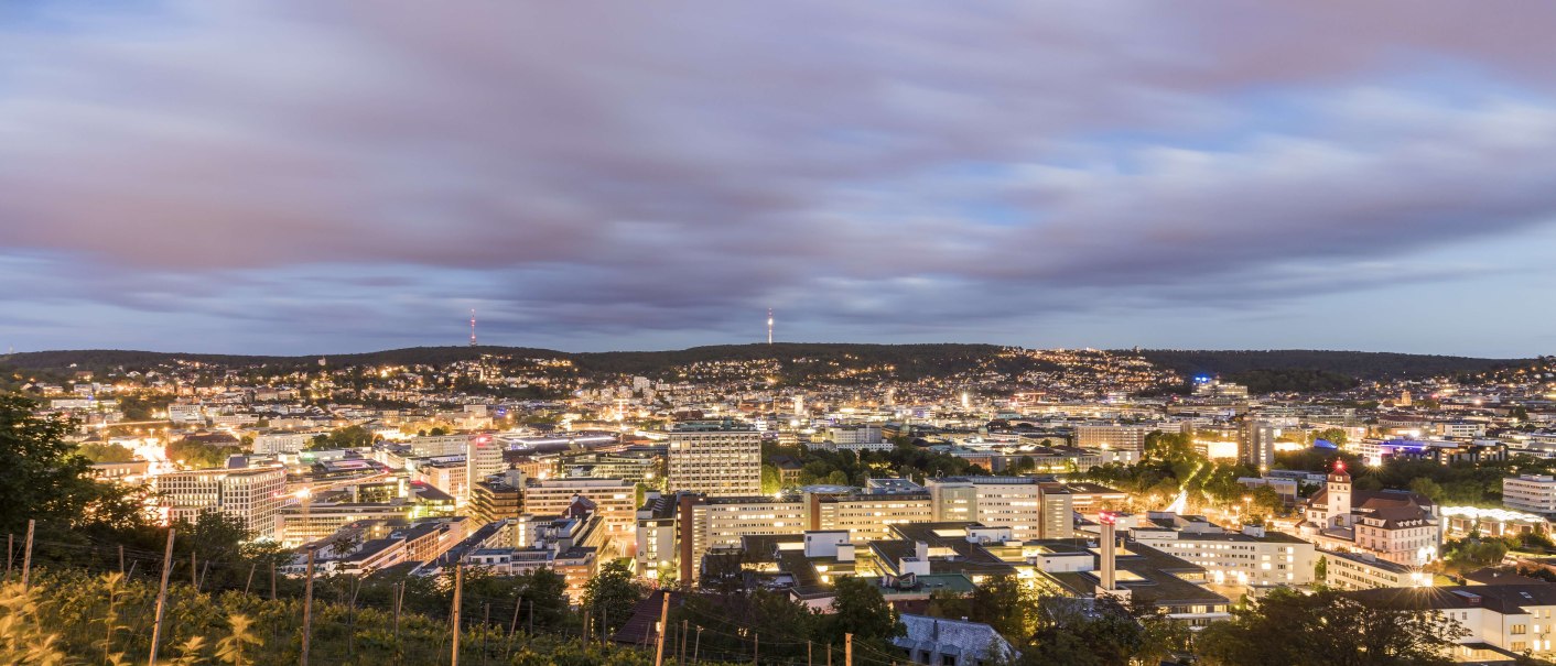 Panorama einer Stadt bei Abenddämmerung, mit beleuchteten Gebäuden und einem bewölkten Himmel im Hintergrund., © SMG, Werner Dieterich Panorama einer Stadt bei Abenddämmerung, mit beleuchteten Gebäuden und einem bewölkten Himmel im Hintergrund., © SMG, Werner Dieterich