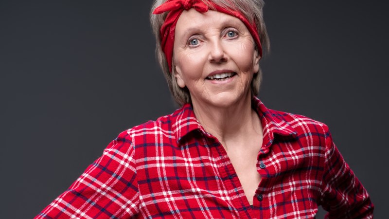 Eine Frau mit rotem Stirnband und kariertem Hemd l&auml;chelt in die Kamera. Der Hintergrund ist dunkelgrau., &copy; jean m. laffitau